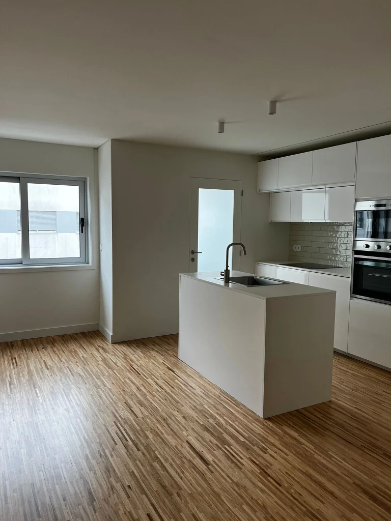 Imagem de uma cozinha completamente remodelada, com design moderno e funcional. A cozinha apresenta armários de linhas clean, bancadas de acabamento elegante, e electrodomésticos de última geração. O espaço é amplo e bem iluminado, com detalhes que valorizam a estética e a praticidade do ambiente.