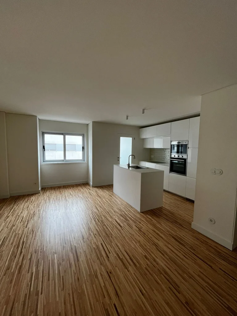Imagem de uma cozinha completamente remodelada, com design moderno e funcional. A cozinha apresenta armários de linhas clean, bancadas de acabamento elegante, e electrodomésticos de última geração. O espaço é amplo e bem iluminado, com detalhes que valorizam a estética e a praticidade do ambiente.
