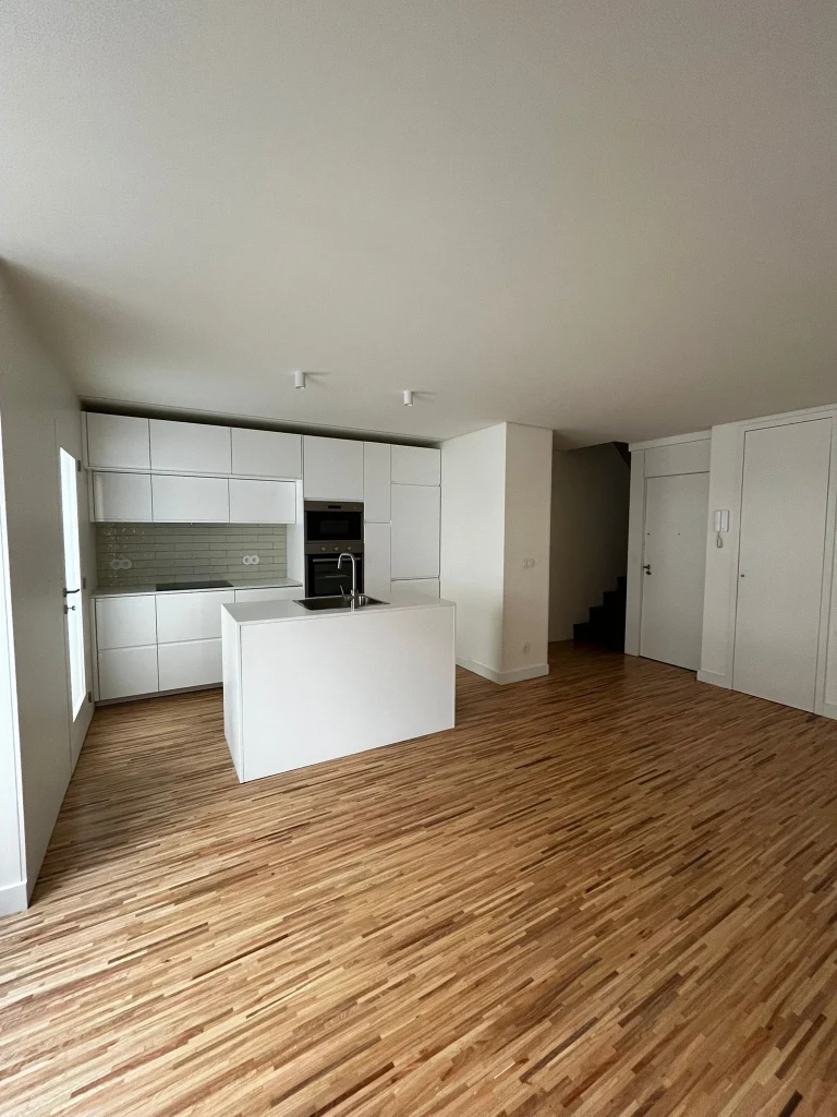 Imagem de uma cozinha completamente remodelada, com design moderno e funcional. A cozinha apresenta armários de linhas clean, bancadas de acabamento elegante, e electrodomésticos de última geração. O espaço é amplo e bem iluminado, com detalhes que valorizam a estética e a praticidade do ambiente.