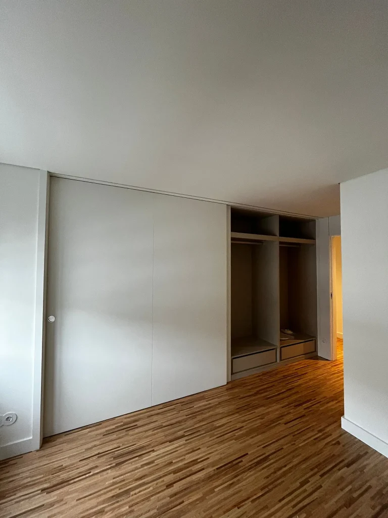 Imagem de um closet moderno e bem organizado, com acabamentos elegantes e distribuição eficiente do espaço. O design privilegia a arrumação e a funcionalidade, proporcionando um ambiente prático e sofisticado, ideal para armazenamento otimizado de roupas e acessórios.