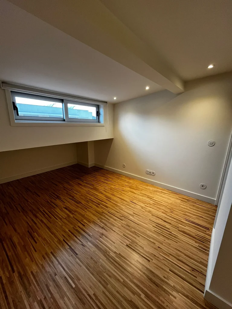Imagem de quartos amplos com pavimento em taco de madeira, destacando o ambiente acolhedor e elegante. A disposição do espaço privilegia a luminosidade natural, enquanto o revestimento confere um toque intemporal e confortável, combinando funcionalidade e estética.