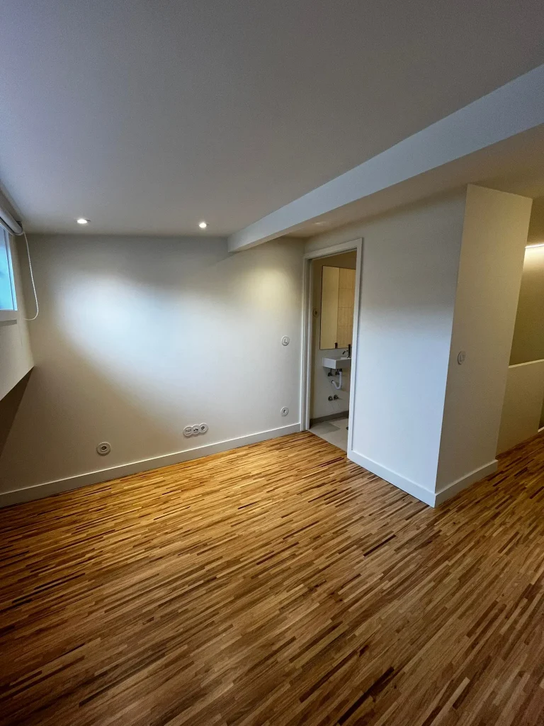 Imagem de quartos amplos com pavimento em taco de madeira, destacando o ambiente acolhedor e elegante. A disposição do espaço privilegia a luminosidade natural, enquanto o revestimento confere um toque intemporal e confortável, combinando funcionalidade e estética.