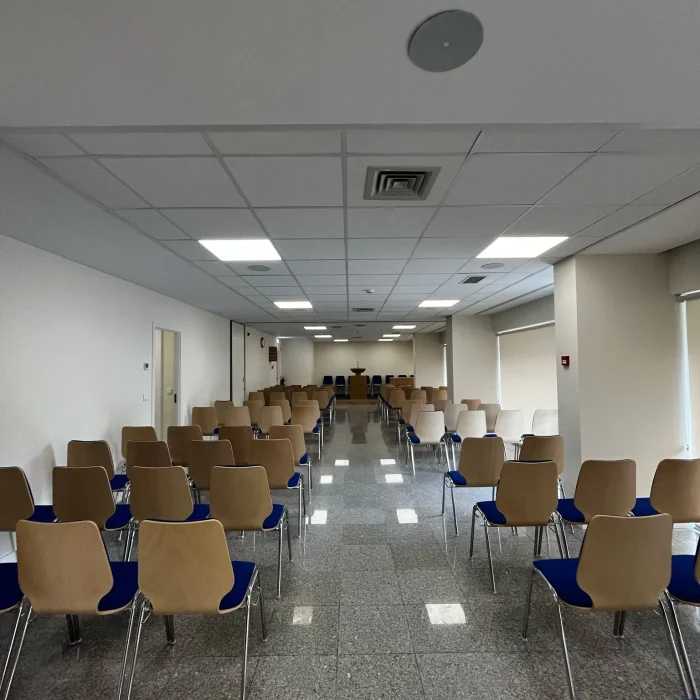 Sala de reuniões renovada da Igreja de Jesus Cristo dos Santos dos Últimos Dias em Barcelos, com cadeiras organizadas em fileiras sobre piso de granito polido. Obra realizada pela empresa Matrice de construção civil, com acabamentos modernos e iluminação eficiente