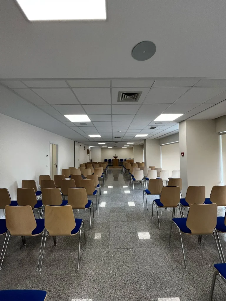 Sala de reuniões renovada da Igreja de Jesus Cristo dos Santos dos Últimos Dias em Barcelos, com cadeiras organizadas em fileiras sobre piso de granito polido. Obra realizada pela empresa Matrice de construção civil, com acabamentos modernos e iluminação eficiente